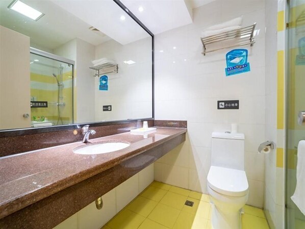 Une salle de bain avec un plan de toilette en marbre, un lavabo blanc, des toilettes blanches et une douche à parois de verre.