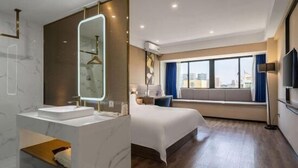Une chambre d’hôtel moderne dotée d’un grand lit, d’une coiffeuse intégrée avec un miroir, d’une fenêtre donnant sur la ville et d’un téléviseur à écran plat.