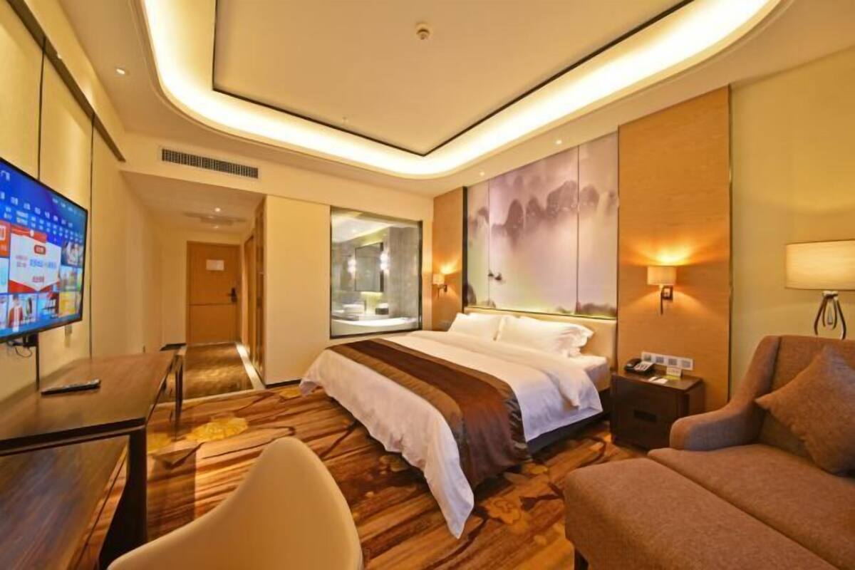 Ein modernes Hotelzimmer mit einem großen Bett, einem Schreibtisch, einem Fernseher und einem Sofa.