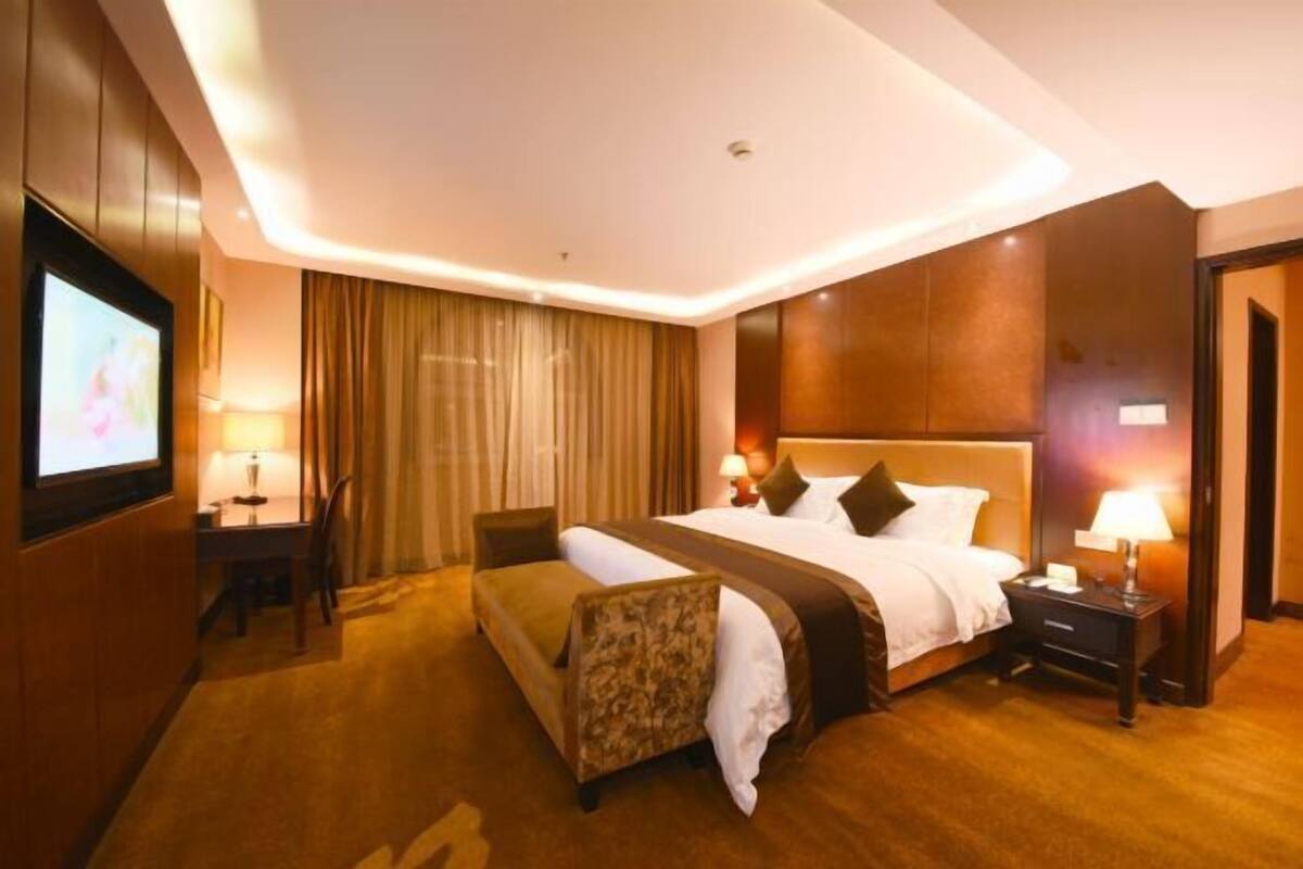 Ein Hotelzimmer mit einem großen Bett, einem Schreibtisch mit Stuhl, einem Fernseher und einem Sofa.