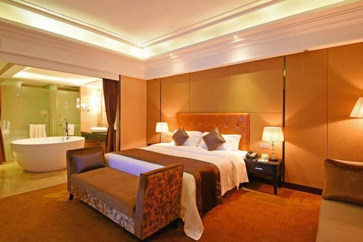 Ein Hotelzimmer mit einem großen Bett, einer separaten Sitzecke, einer Badewanne und einem eigenen Badezimmer.