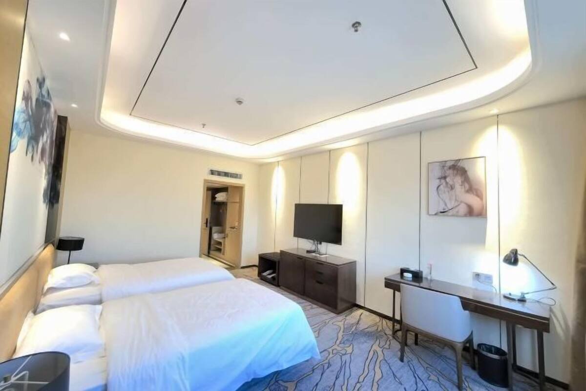 Ein Hotelzimmer mit Bett, Schreibtisch, Fernseher und Kleiderschrank.