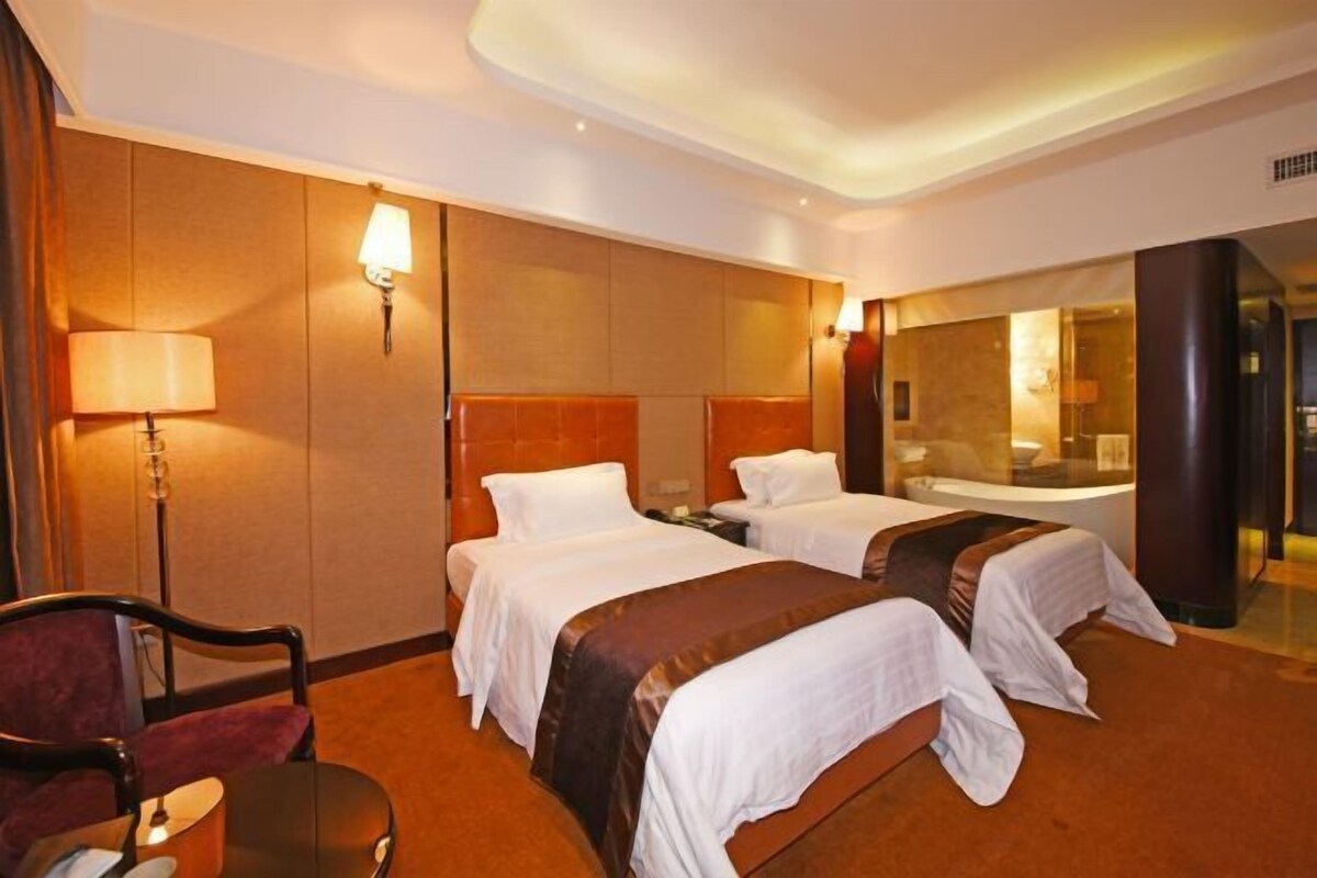 Une chambre d’hôtel avec deux lits, un bureau, une chaise et un miroir.