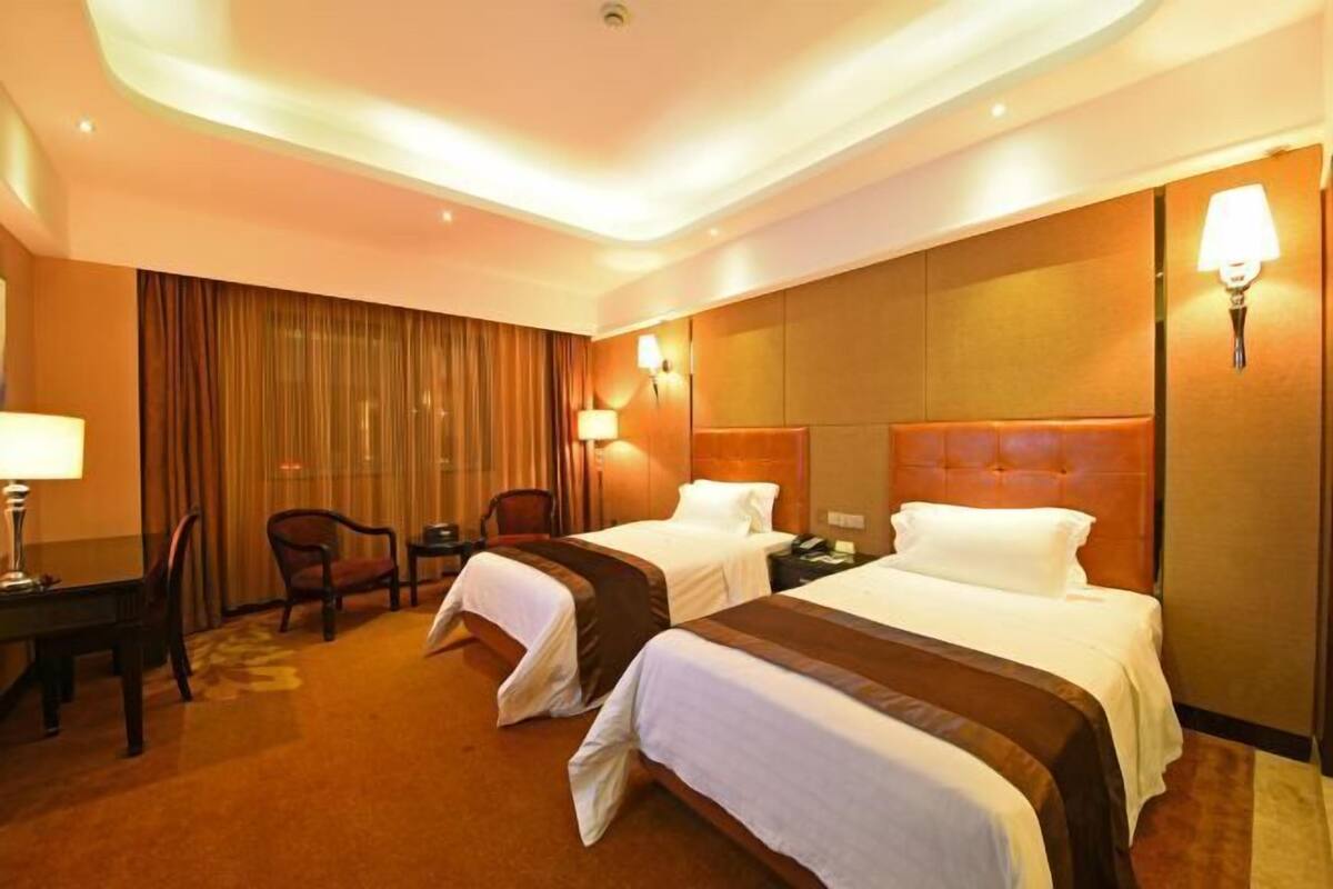 Ein Hotelzimmer mit zwei Betten, einem Schreibtisch, einem Stuhl und einer Lampe.
