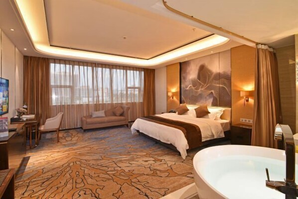 Une chambre d’hôtel dotée d’un grand lit, d’un coin salon avec un canapé, d’un bureau avec une chaise, d’une grande fenêtre avec des rideaux et d’une baignoire.