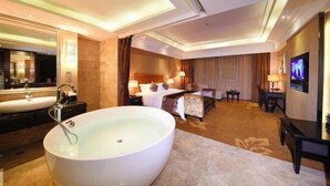 Een hotelkamer met een groot bad, een bed, een bureau en een televisie.