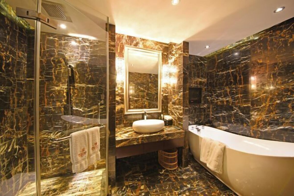 Une salle de bain dotée d’une douche à parois de verre, d’un meuble-lavabo en marbre, d’un évier et d’une baignoire sur pieds.