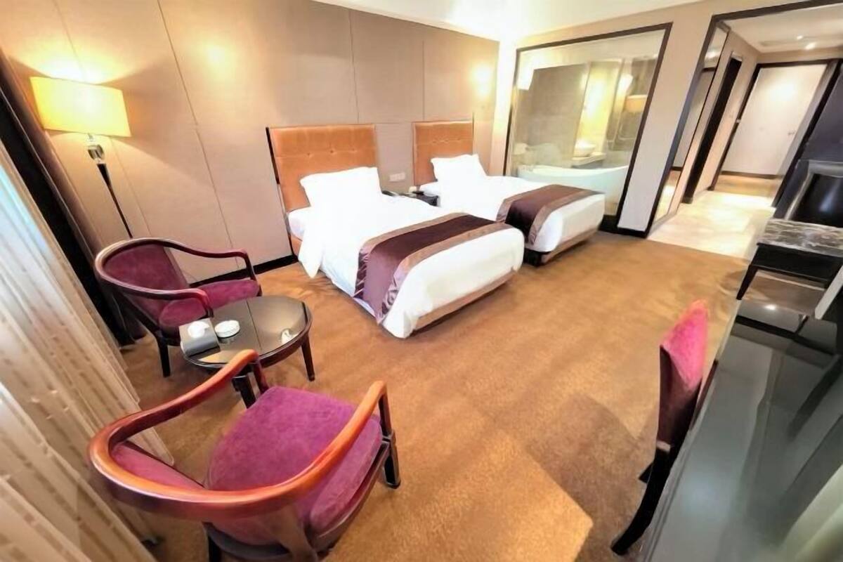 Ein Hotelzimmer mit zwei Betten, einem Schreibtisch, einem Stuhl und einem Fernseher.