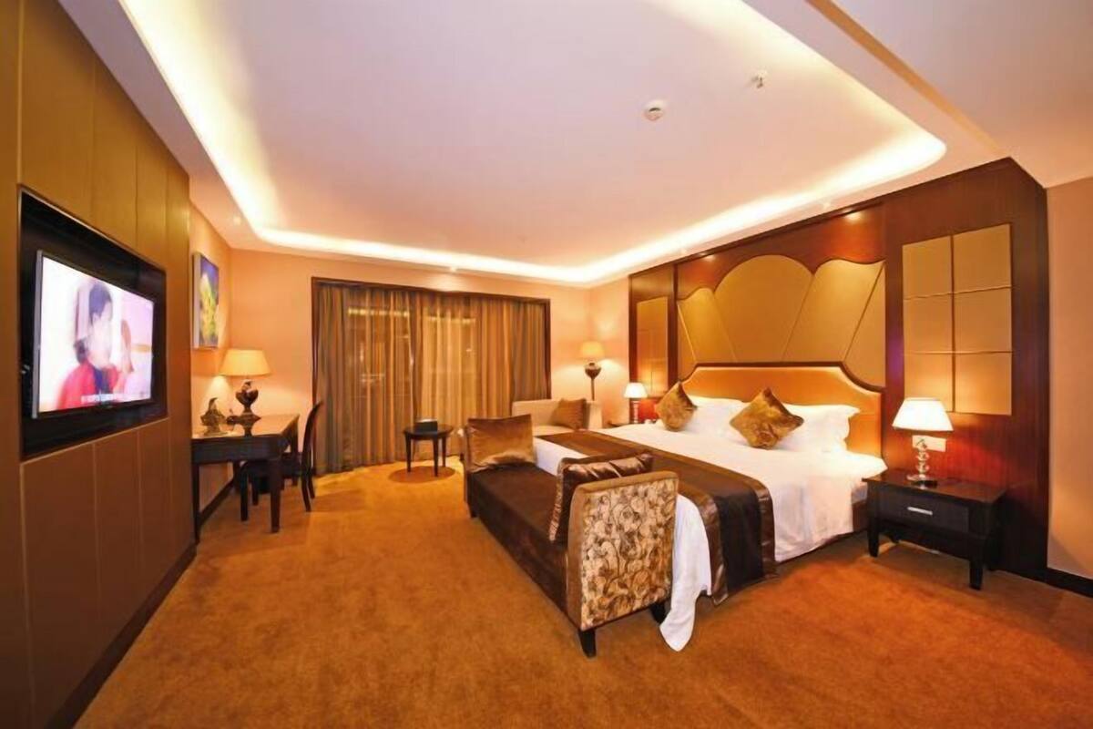 Ein Hotelzimmer mit einem großen Bett, einer Couch, einem Fernseher und einem Schreibtisch.