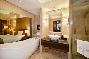 Une salle de bain moderne dans un hôtel, équipée d’une baignoire, d’un lavabo et d’une douche.