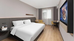 A hotel room with a large bed, a bedside table, a small desk, a chair, and a large TV screen. - Jinjiang Inn (Wenzhou Railway Station) (Wenzhou)