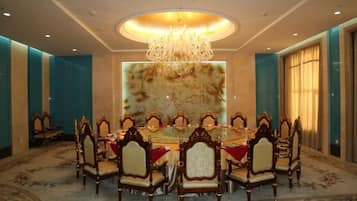 A conference room with a round table, ornate chairs, and a chandelier.