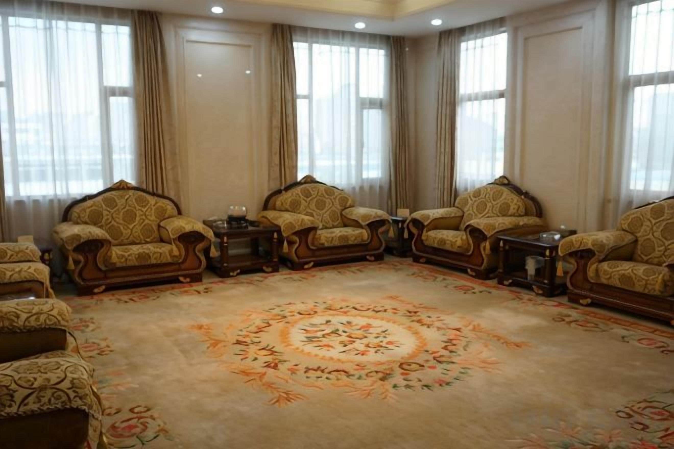 A room with four armchairs, a coffee table, and a large floral carpet.
