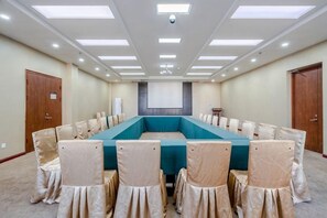 A conference room with a long table, chairs, and a projector screen. - Furunge Hotel (Qingdao)