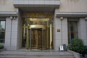 A building entrance with a revolving door, a sign with Chinese characters, and a small signboard on the right. - Furunge Hotel (Qingdao)