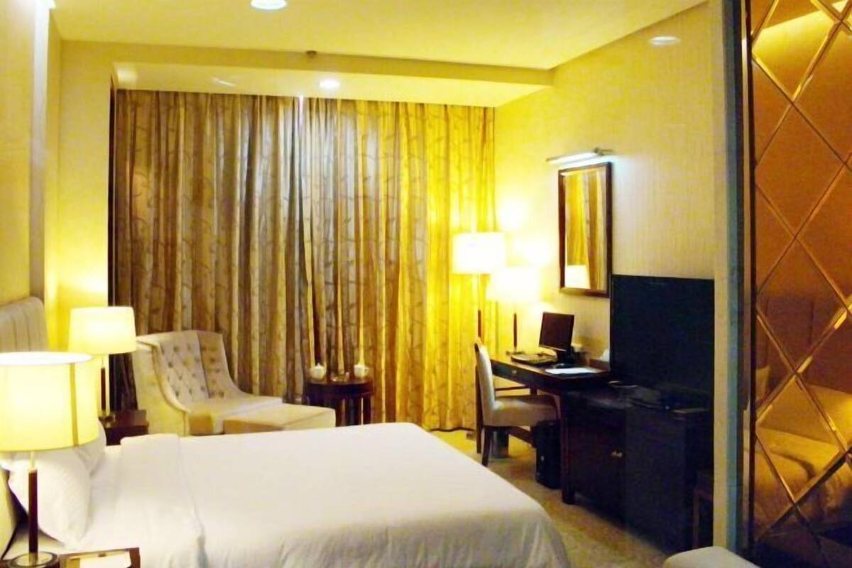 Una habitación de hotel con cama, escritorio, silla, lámpara y televisión.