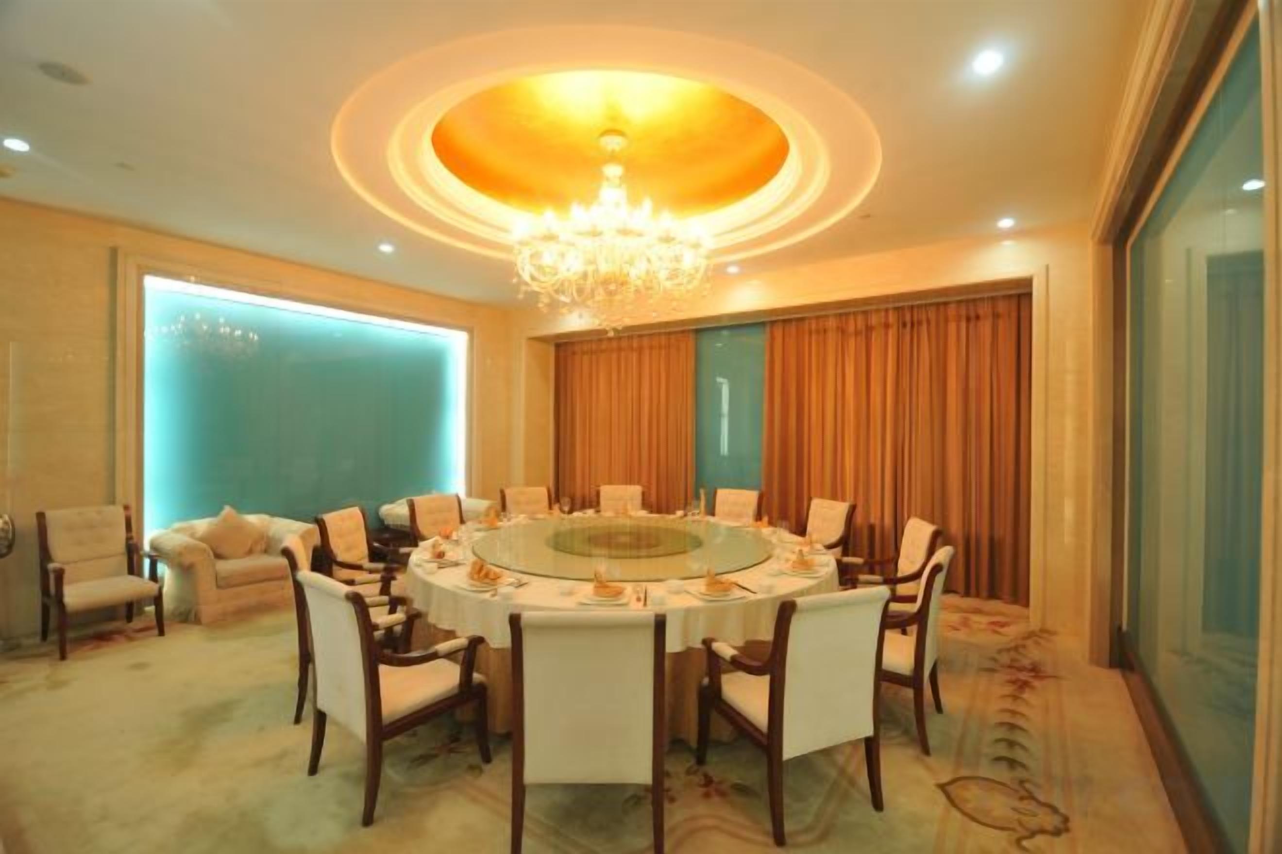 A conference room with a round table, chairs, and a chandelier.
