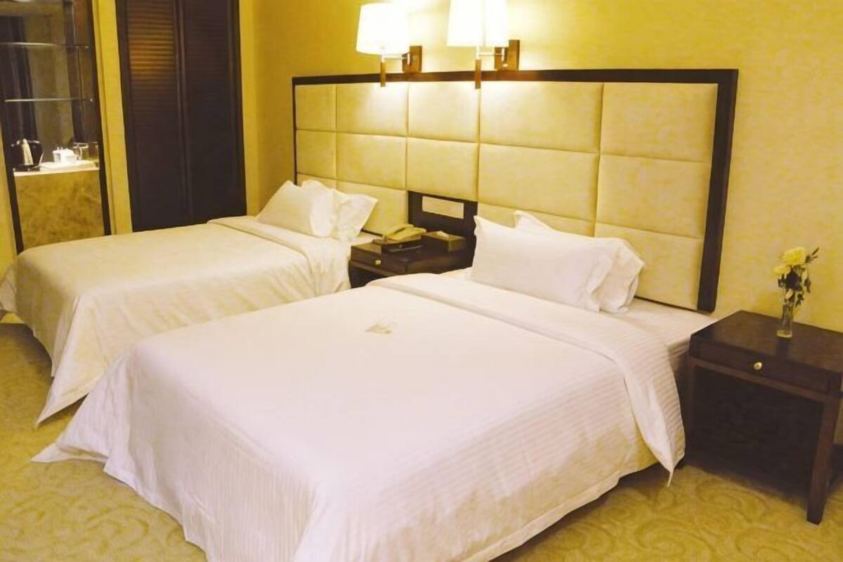Habitación de hotel con dos camas, una mesita de noche y una lámpara.