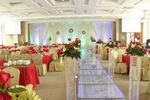 A banquet hall with round tables, chairs, and floral centerpieces.