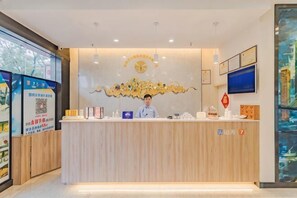 A reception desk with a receptionist, a clock, and framed certificates on the wall. - Golden Season Chain Hotel (Huizhou)