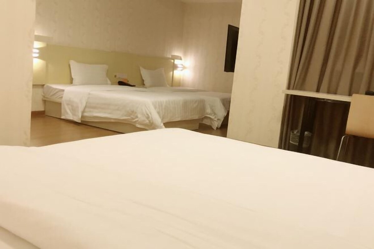A hotel room with a bed, a nightstand, and a lamp.
