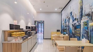 A modern hotel lobby with a reception desk, seating area, and a mural of city buildings. - Golden Season Chain Hotel (Huizhou)