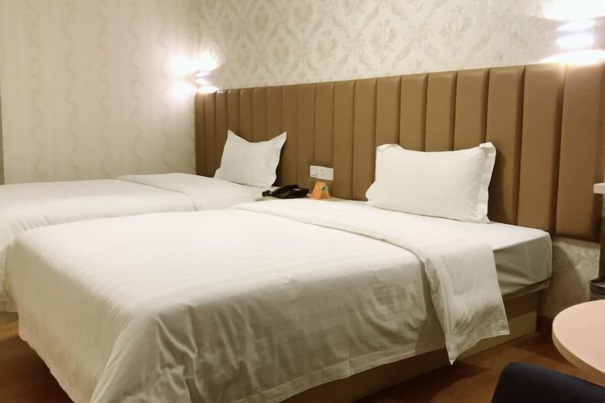 A hotel room with two beds, a round table, and a patterned wallpaper.