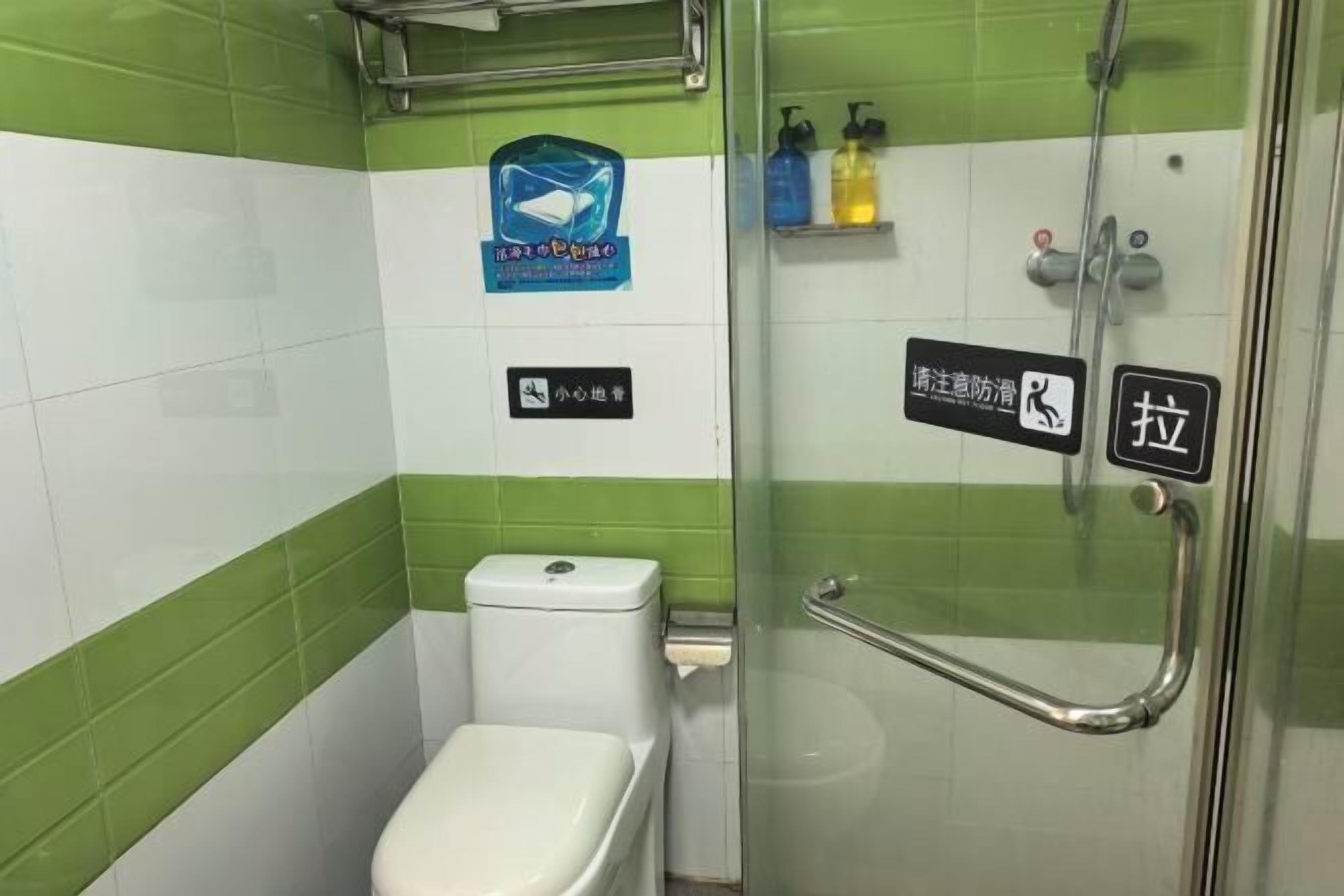 Et badeværelse med toilet, glasbrusekabine og gelænder.