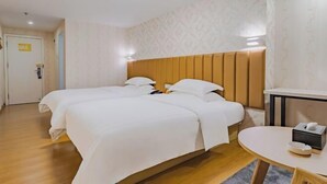 A hotel room with two beds, a small table, and a headboard. - Golden Season Chain Hotel (Huizhou)