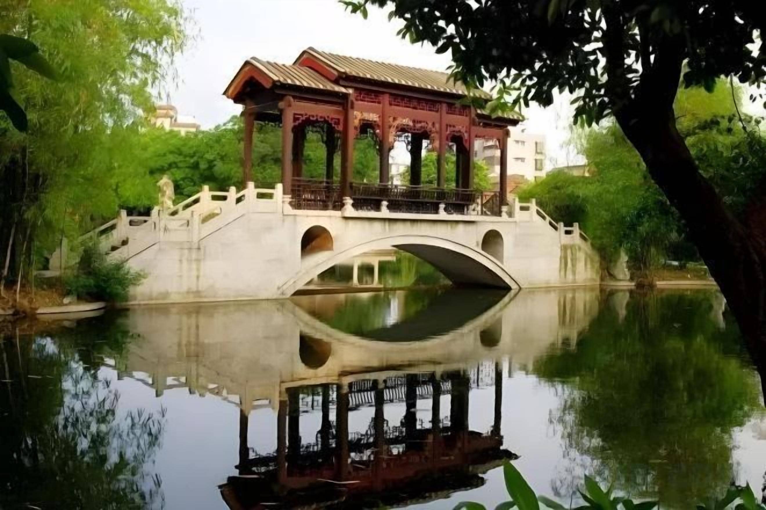 A traditional pavilion over a calm water body, reflecting the structure and surroundings.