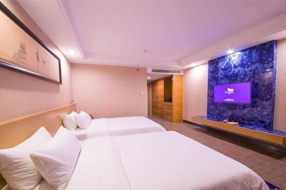 Une chambre d’hôtel avec deux lits, une télévision et un mur en marbre.