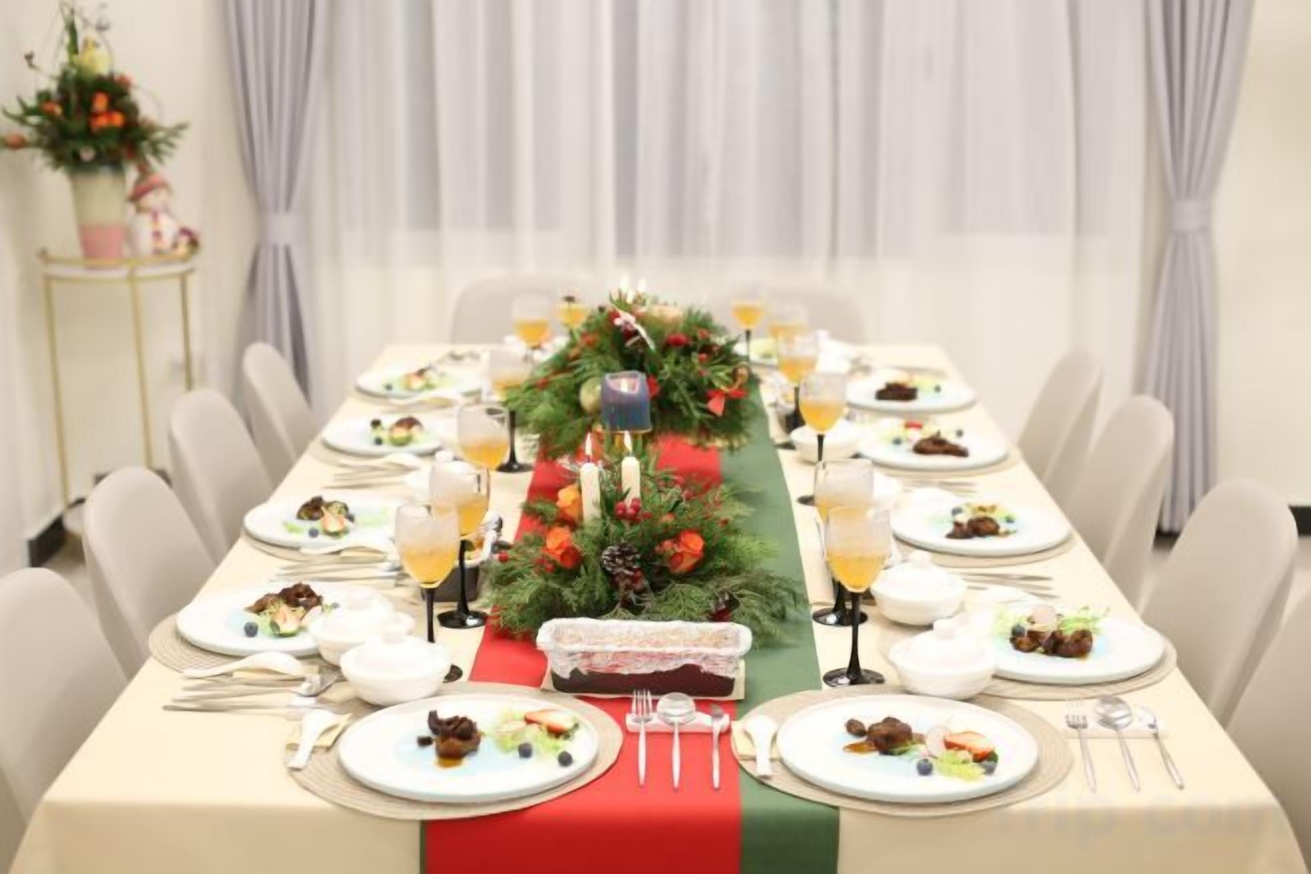 A long dining table set for a meal with a centerpiece, plates, cutlery, and glasses.