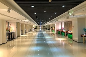 A long, well-lit corridor with a polished floor, doors on the left, and a counter with plants on the right. - Oriental Yucai Hotel (Foshan Ceramics Headquarters Base Huyong Subway Station) (Foshan)
