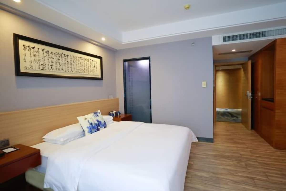 Une chambre d’hôtel comprenant un lit, une table de chevet, des œuvres d’art murales et une porte donnant sur une autre pièce.