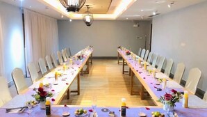 Een congreszaal met lange tafels gedekt voor een vergadering, voorzien van stoelen, tafels en decoraties.