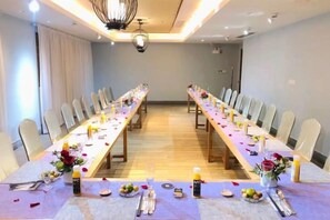 Une salle de conférence avec une longue table, des chaises et un lustre.
