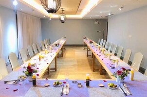 Un salón de conferencias con una larga mesa, sillas y una lámpara de araña.