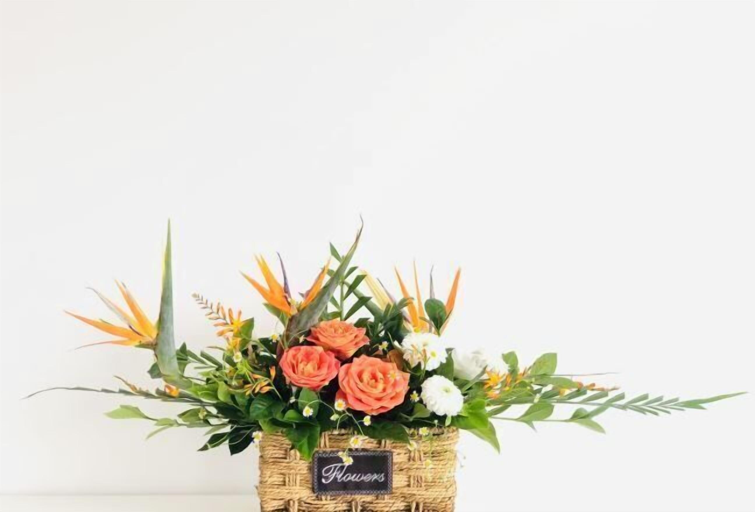 Ein Korankorb, gefüllt mit verschiedenen Blumen und Grünpflanzen, mit dem Aufdruck 'Flowers'.