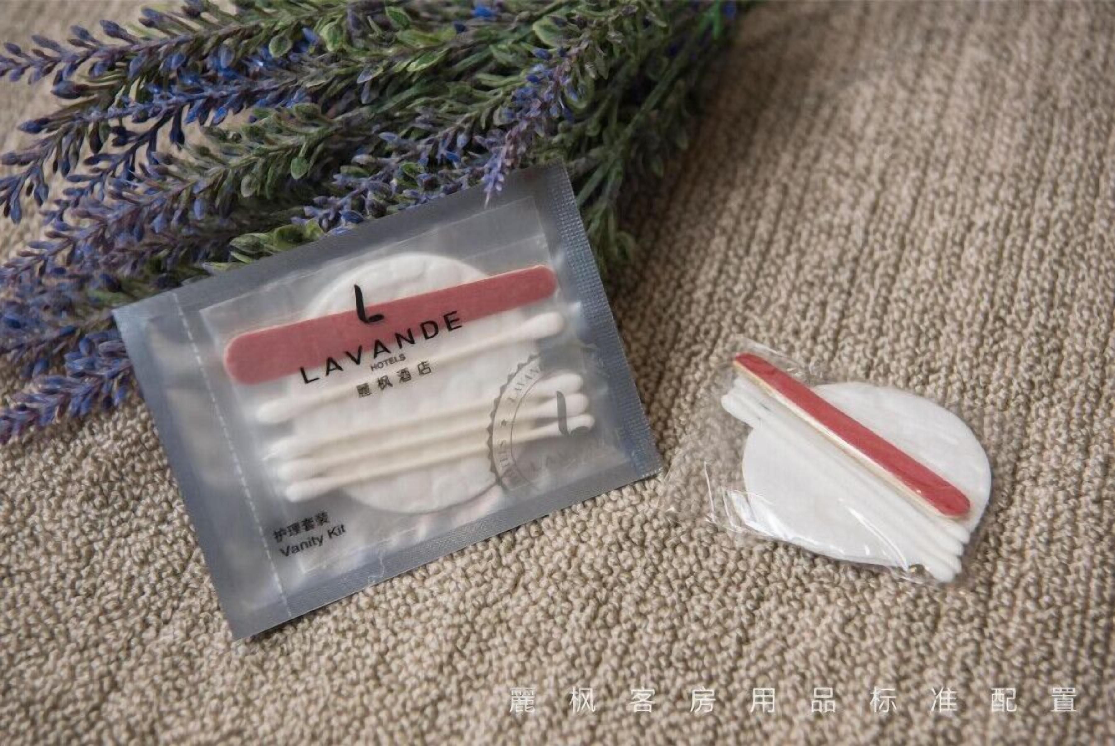 A lavender vanity kit with a red handle, a white cotton pad, and a white cotton swab.