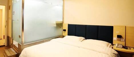 Een hotelkamer met een bed, nachtkastje, telefoon en een schuifdeur.