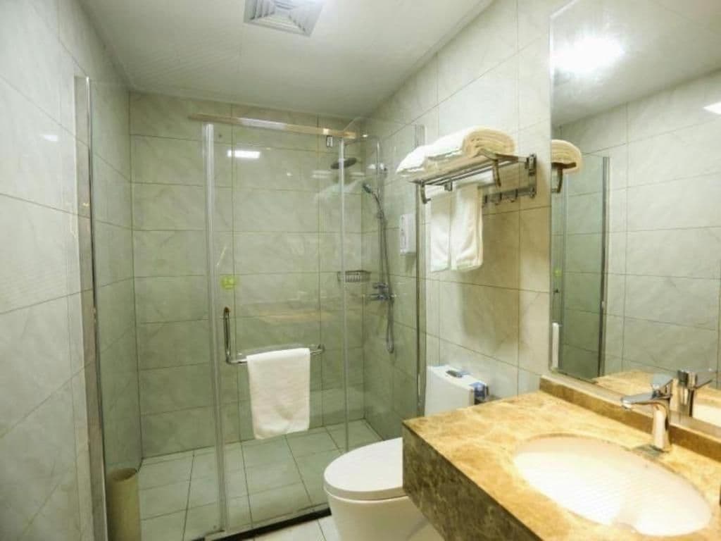 A bathroom with a glass-enclosed shower, a toilet, and a sink with a marble countertop.