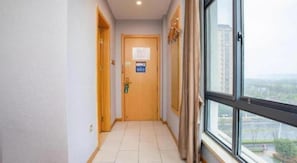 A corridor with a wooden door, a window with a view, and a sign on the wall.