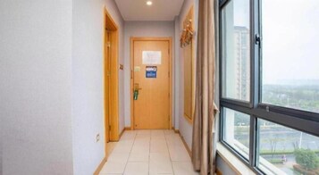 Un pasillo con una puerta de madera, un ventanal con vistas y un cartel en la pared.