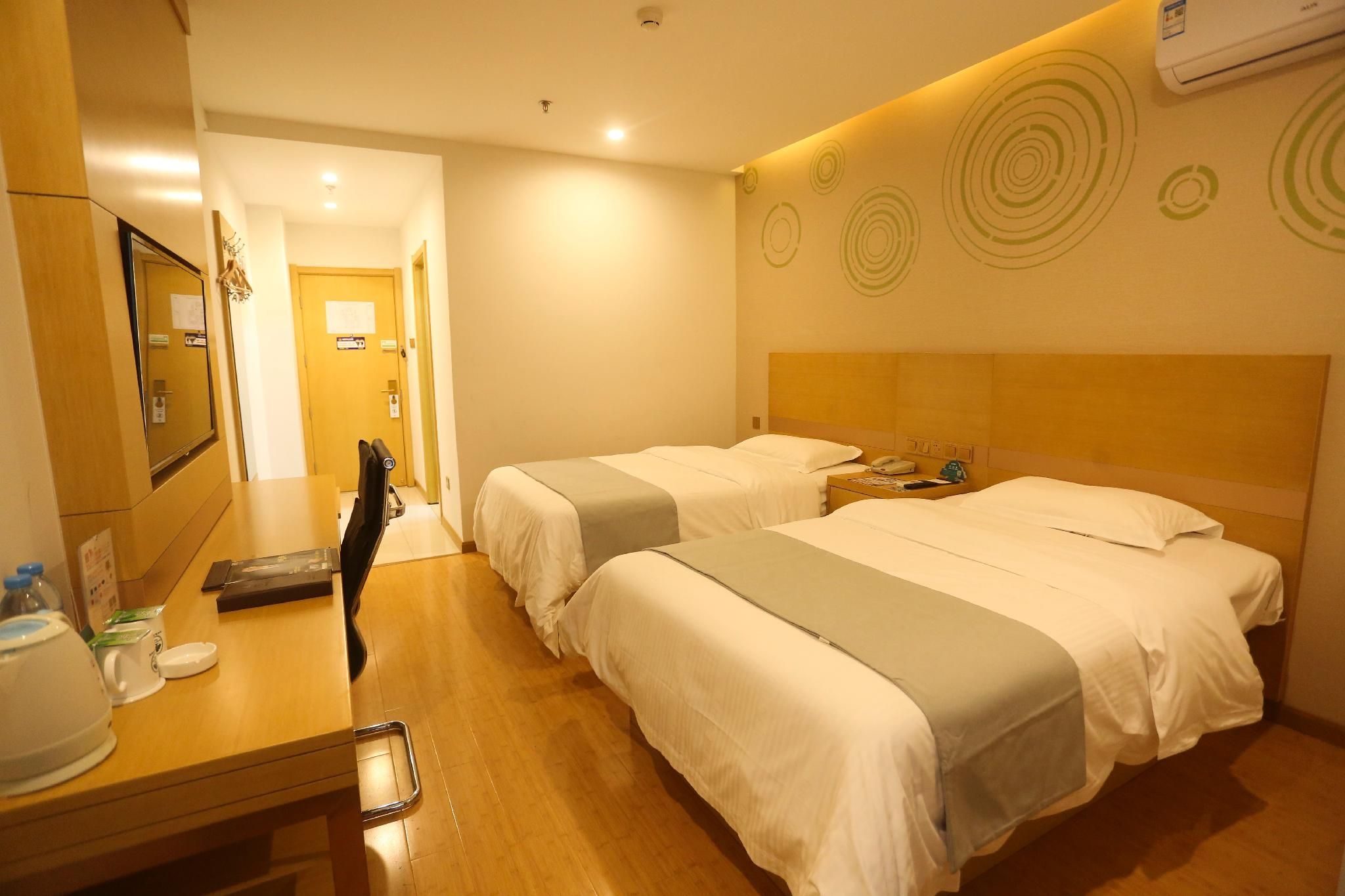 Habitación de hotel con dos camas, un escritorio con teléfono y un espejo.