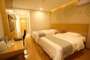 Een hotelkamer met twee bedden, een bureau met telefoon en een spiegel.