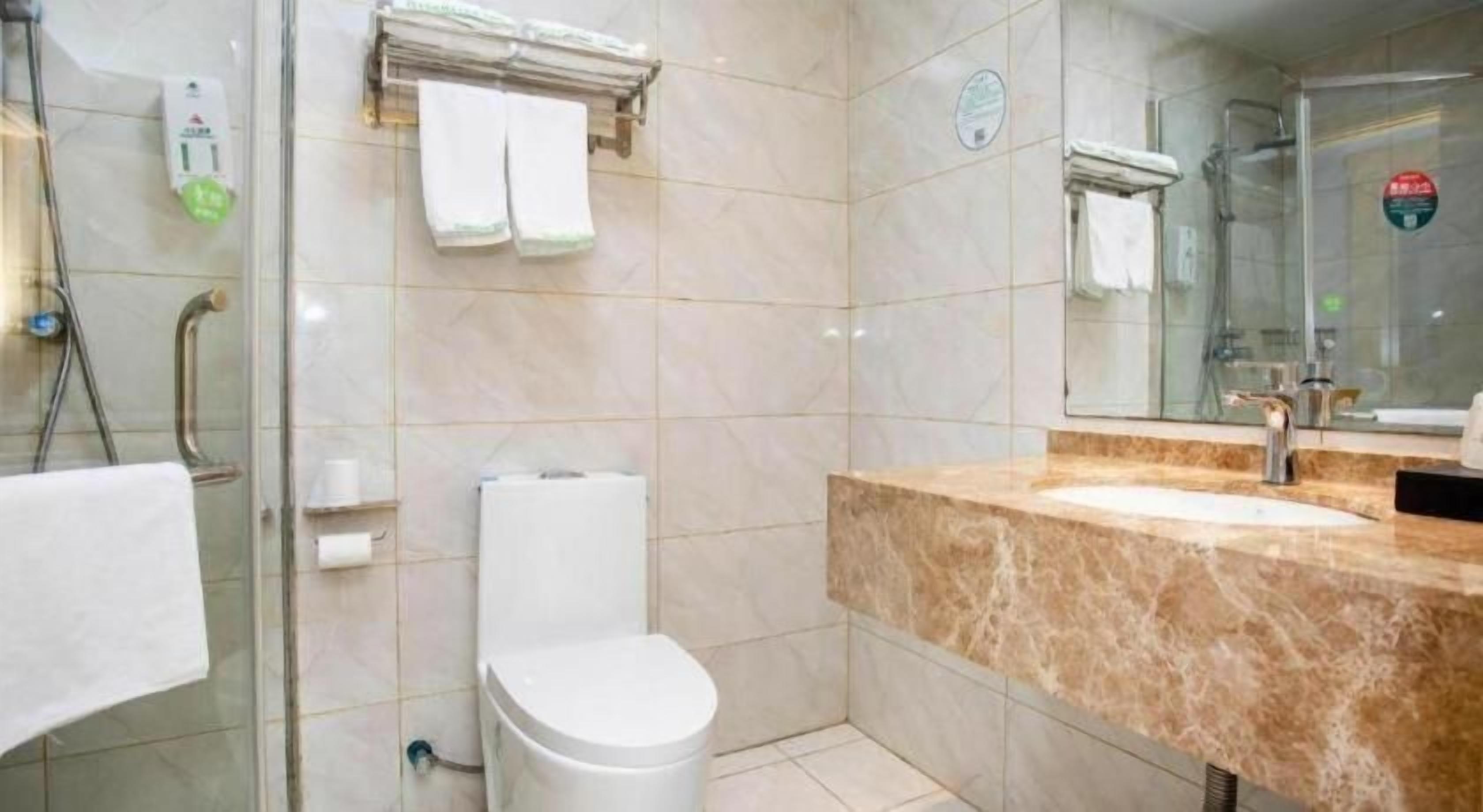 Un baño con cabina de ducha de vidrio, inodoro, lavabo con encimera de mármol y espejo.