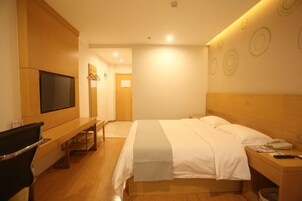 Una habitación de hotel con cama, mesita de noche, televisor y escritorio con silla.