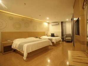 A hotel room with two beds, a desk, and a chair.