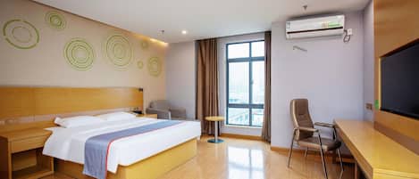 Habitación de hotel con cama, escritorio, silla y un amplio ventanal.