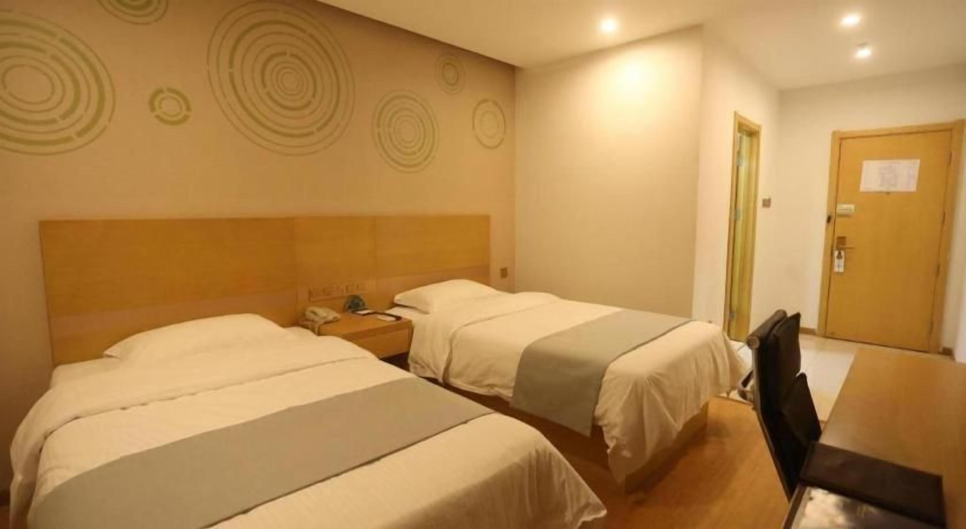 A hotel room with two beds, a desk, and a chair.
